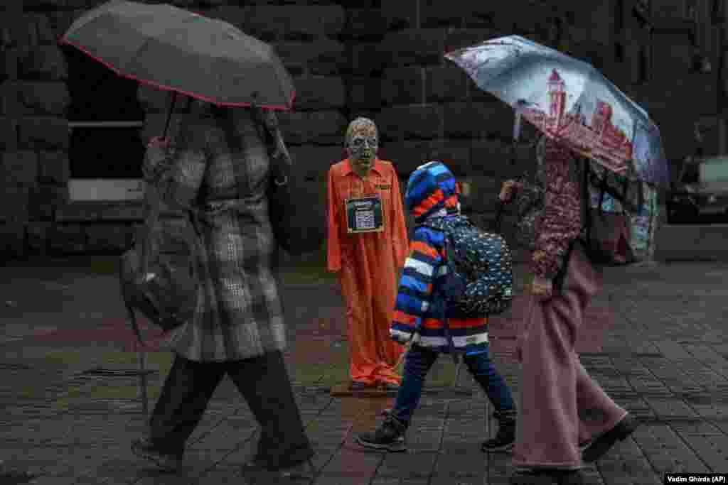 People walk by an effigy of Russian President Vladimir Putin dressed in a prisoner outfit in Kyiv.