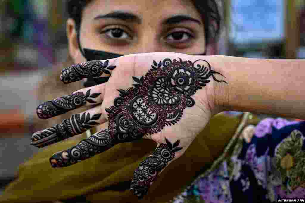 A woman poses after getting her hands decorated with henna at a beauty salon in Karachi, Pakisdtan, ahead of the Eid al-Fitr festival marking the end of the holy fasting month of Ramadan.