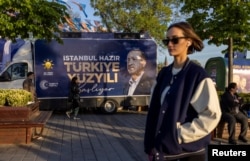 Женщина проходит мимо предвыборного автомобиля с изображением президента Турции Тайипа Эрдогана и лозунгом «Век Турции начинается. Стамбул готов». Стамбуле, 2 мая 2023 года