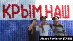 Мужчины в бескозырках на фоне композиции «Крым наш» в Севастополе. Крым, 2016 год
