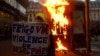 Maskirani prosvjednik stoji kraj vatre usred sukoba tokom prosvjeda u sklopu devetog dana štrajkova diljem zemlje protiv penzione reforme francuske vlade, u Parizu, Francuska, 23. marta 2023.