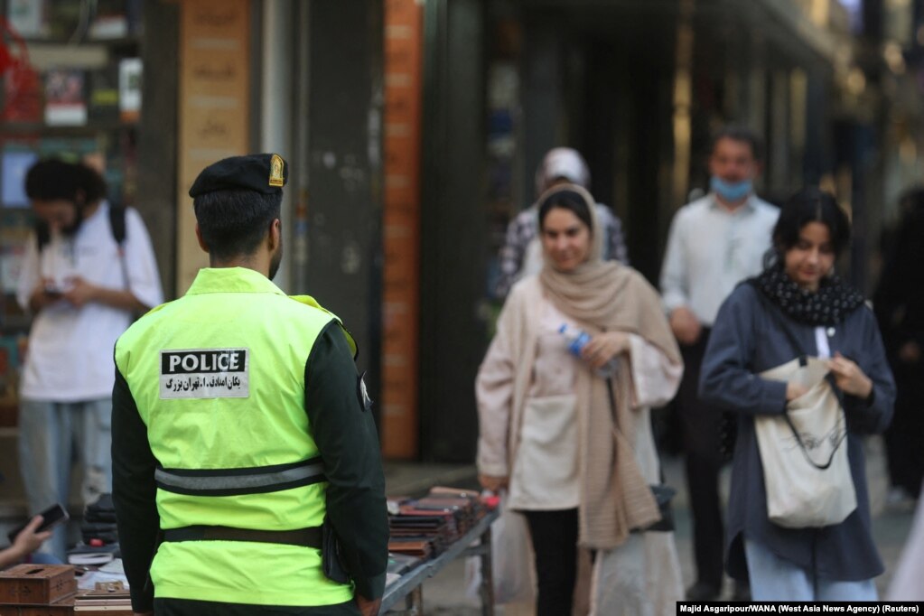Një polic në Teheran dhe një grua që ec me kokën zbuluar. &nbsp;
