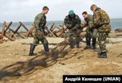 Прикордонники України встановлюють протитанкові загородження (так звані «їжаки») на українському острові Тузла під час територіального конфлікту з Росією, 9 жовтня 2003 року