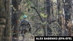 Ukrán katona sétál az erdőben egy meg nem nevezett helyen, a frontvonal mentén Donyeck irányába 2023. június 28-án
