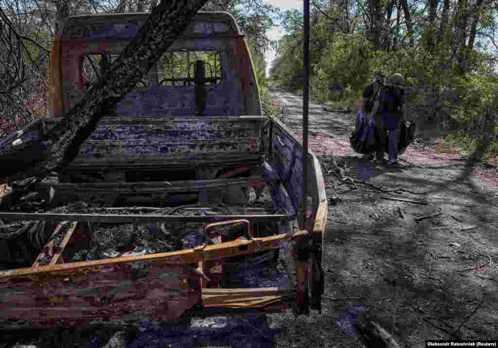 Volodymyr, a 50-year-old marine (right), and a colleague carry the body of a dead Russian soldier near a burned-out truck. &quot;We&#39;re going to search with our eyes. And using smell,&quot; he said. To make sure the bodies are not booby-trapped by the withdrawing Russian forces, the soldiers frequently resort to probing the bodies with sticks. &nbsp;