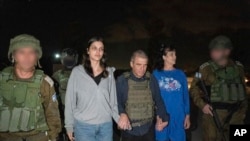Judith Raanan (jobbra) és 17 éves lánya, Natalie, amint izraeli katonák mellett a fogvatartottakért és eltűntekért felelős izraeli kormánykoordinátor visszakíséri őket Izraelbe 2023. október 20-án
