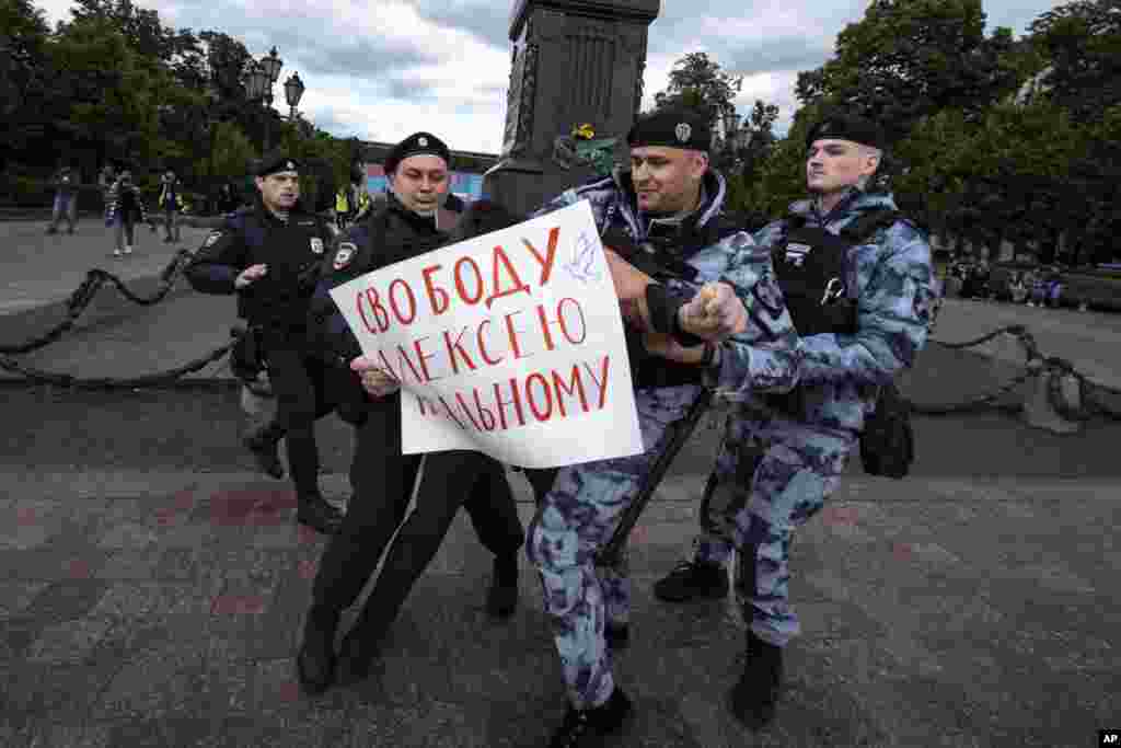 Полицаец приведува демонстрант со постер на кој пишува: &bdquo;Слобода за Алексеј Навални&ldquo; на плоштадот Пушкинскаја во Москва, на одвележувањето на роденденот на затворениот руски опозииски активист.