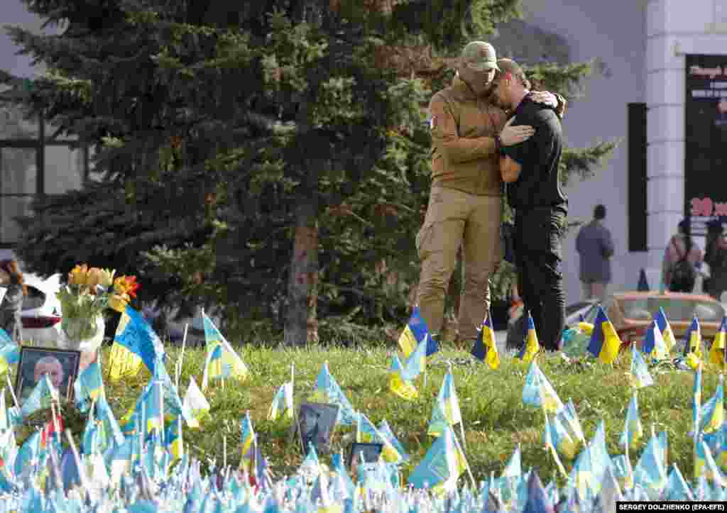 Two men embrace near the flags placed on Independence Square in commemoration of fallen Ukrainian soldiers in downtown Kyiv on October 30.