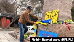 Алматинский активист Марат Турымбетов возлагает цветы и флаг Украины к памятнику Тараса Шевченко. 24 февраля 2023 года