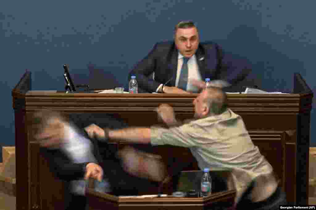 The leader of the ruling Georgian Dream party&#39;s group in parliament, Mamuka Mdinaradze (left), is punched in the face by opposition deputy Aleksandr Elisashvili while speaking in parliament in Tbilisi on April 15, amid debate over the contentious &quot;foreign agents&quot; bill.