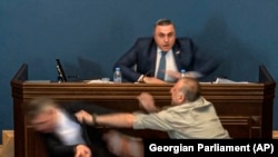 Opposition lawmaker Aleksander Elisashvili (right) attackeg ruling Georgian Dream leader Mamuka Mdinaradze (left) at the speaker's rostrum of the Georgian parliament on April 15 during debate over the "foreign agents" bill.