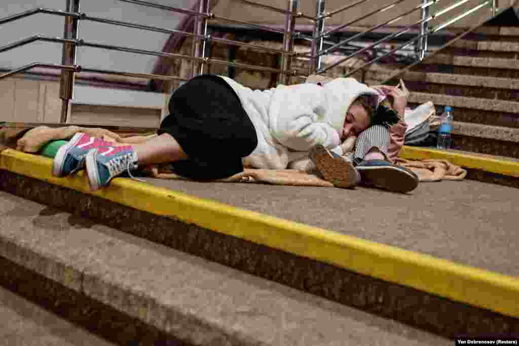 People sleep on stairs as they take shelter inside a subway station during an overnight Russian missile and drone strike in the Ukrainian capital, Kyiv.&nbsp;