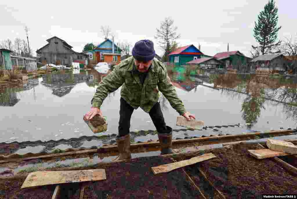 A man works to protect his vegetable garden from encroaching floodwater. Flooding has also been reported across Siberia, the Volga, and central regions of Russia.