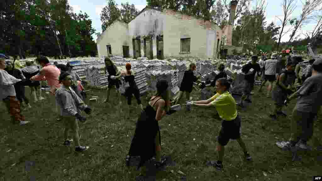 A Javítsuk meg Együtt&nbsp;jótékonysági szervezet önkéntesei egy lerombolt kulturális központ használható tégláit gyűjtik össze a csernyihivi Jahidne faluban 2023. július 8-án