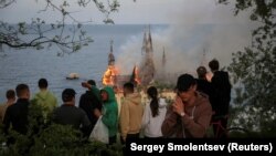 Emberek nézik a lángokban álló és a helyiek által Harry Potter-kastélynak nevezett jogi akadémiát Odesszában 2024. április 29-én