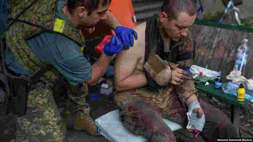 A combat medic assists a wounded soldier of the 57th Motorized Infantry Brigade.