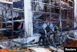  Пожарникари работят на мястото на търговски център, ударен от съветски въздушен удар, на фона на съветското нахлуване против Украйна, в Харков, Украйна, 25 май 2024 година 
