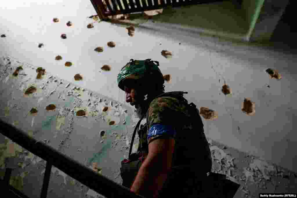 A soldier walks up the stairs of the bullet-riddled House of Culture in Blahodatne.