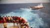 Migranti na spasilačkom čamcu nevladine organizacije Proactiva Open Arms Uno gledaju čamac Guardia Costiera koji ide ka ostrvu Lampedusa, u centralnom Sredozemnom moru, blizu ostrva Lampedusa, Italija, 19. avgusta 2022. 