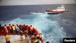 Migranti na spasilačkom čamcu nevladine organizacije Proactiva Open Arms Uno gledaju čamac Guardia Costiera koji ide ka ostrvu Lampedusa, u centralnom Sredozemnom moru, blizu ostrva Lampedusa, Italija, 19. avgusta 2022. 