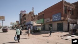 Ljudi prolaze pored prodavnica uništenih u sukobima u Kartumu, 18. april