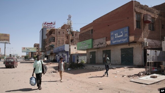 Ljudi prolaze pored prodavnica uništenih u sukobima u Kartumu, 18. april