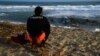 Спасител на италианския бряг гледа останките от дървената лодка