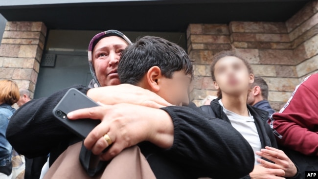 Женщина прижимает к себе сына после убийства учителя в Аррасе. Франция. 13 октября 2023 года