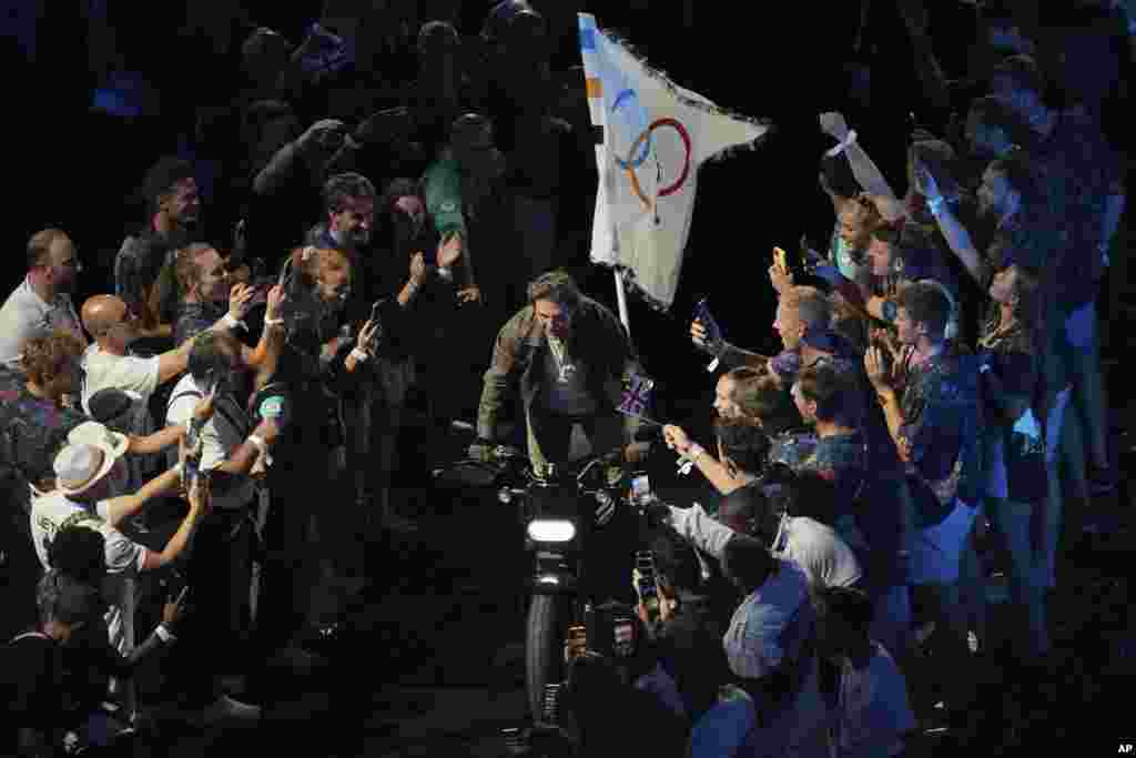 După ce preluat în mod simbolic steagul olimpic de la gimnasta americană&nbsp;Simone Biles, actorul Tom Cruise a ieșit din stadion pe motocicletă, a mers pe străzile Parisului către un aeroport și, într-o călătorie preînregistrată cu un avion militar, a sărit deasupra orașului Los Angeles. Organizatorii americani și-au propus ca, prin Jocurile Olimpice din 2028 de la Los Angeles, să limiteze traficul în oraș: locațiile olimpice ar urma să fie accesibile doar cu transportul public.