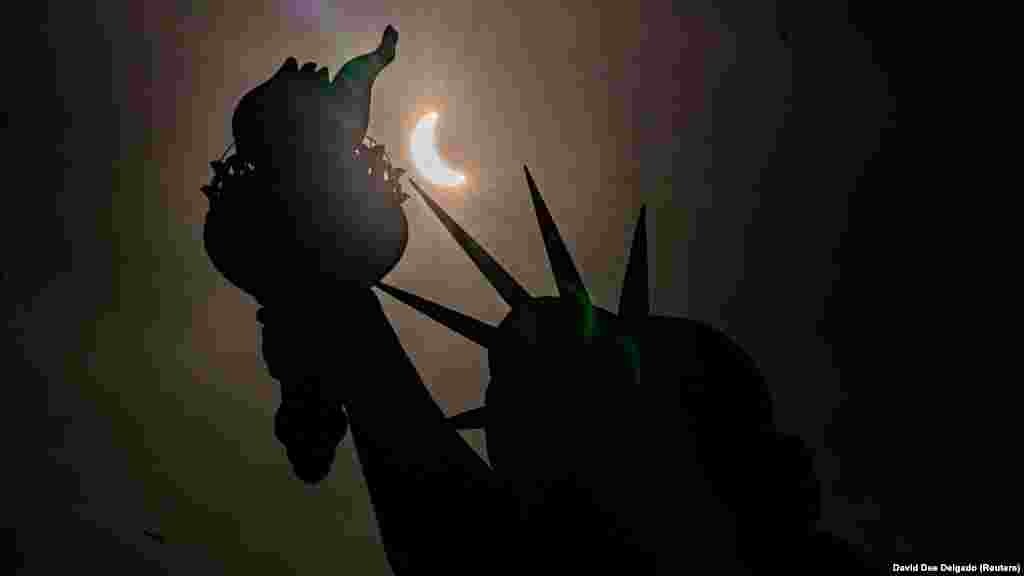 A Szabadság-szobor részleges napfogyatkozás közben, amikor a Hold részben eltakarja a Napot New Yorkban 2024. április 8-án délután.&nbsp;New York egyike annak a tizenegy amerikai államnak, amely a teljes napfogyatkozás útvonalán belül helyezkedik el. New York városában részlegesen volt látható a csillagászati esemény
