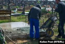 Vova Chekh and a worker pour concrete onto a new grave at Yatseve Cemetery.