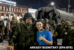 A woman poses with Wagner fighters as they prepare to leave downtown Rostov-on-Don on June 24.
