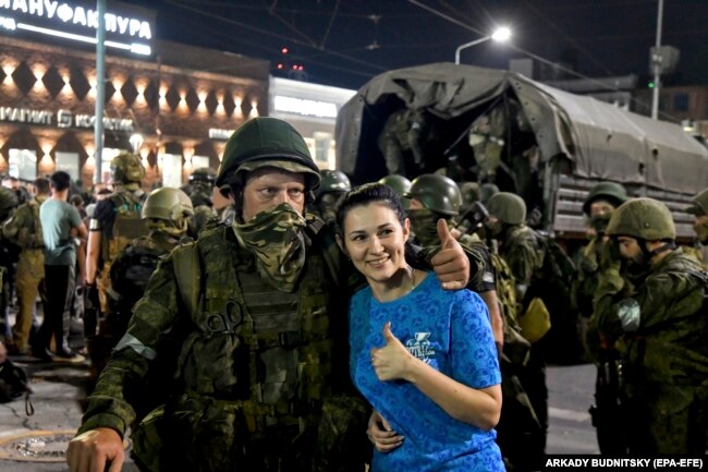 A woman poses with Wagner fighters as they prepare to leave downtown Rostov-on-Don on June 24.