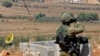 سرباز اسرائیلی در مرز لبنان و پرچم حزب‌الله که در گوشه تصویر دیده می‌شود 