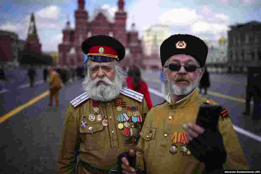 Two men in Russian Cossack uniforms pose after visiting the mausoleum of Soviet founder Vladimir Lenin marking the 154th anniversary of his birth, on Red Square in Moscow.