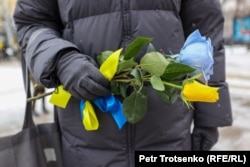 Женщина держит жёлто-голубой букет в день второй годовщины нападения России на Украину. Алматы, 24 февраля 2024 года