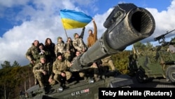 Ukrán katonák ukrán zászlóval egy Challenger 2 típusú harckocsi tetején kiképzés közben Bovington Campben, Nagy-Britannia délnyugati részén 2023. február 22-én