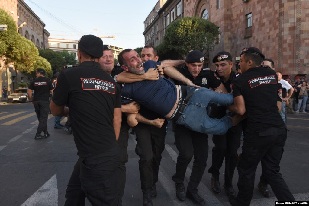 Policia armene ndalon një protestues jashtë ndërtesës së qeverisë në Jerevanin qendror më 8 gusht. Policia armene arrestoi disa protestues, kryesisht veteranë lufte, pasi bllokuan një ndërtesë qeveritare, duke kërkuar nga autoritetet të ndërmarrin hapa për t&#39;i dhënë fund bllokadës së korridorit të Laçin nga Azerbajxhani. Korridori i Laçinit është rruga e vetme që lidh rajonin separatist të populluar nga armenët të Nagorno-Karabakut me Armeninë.