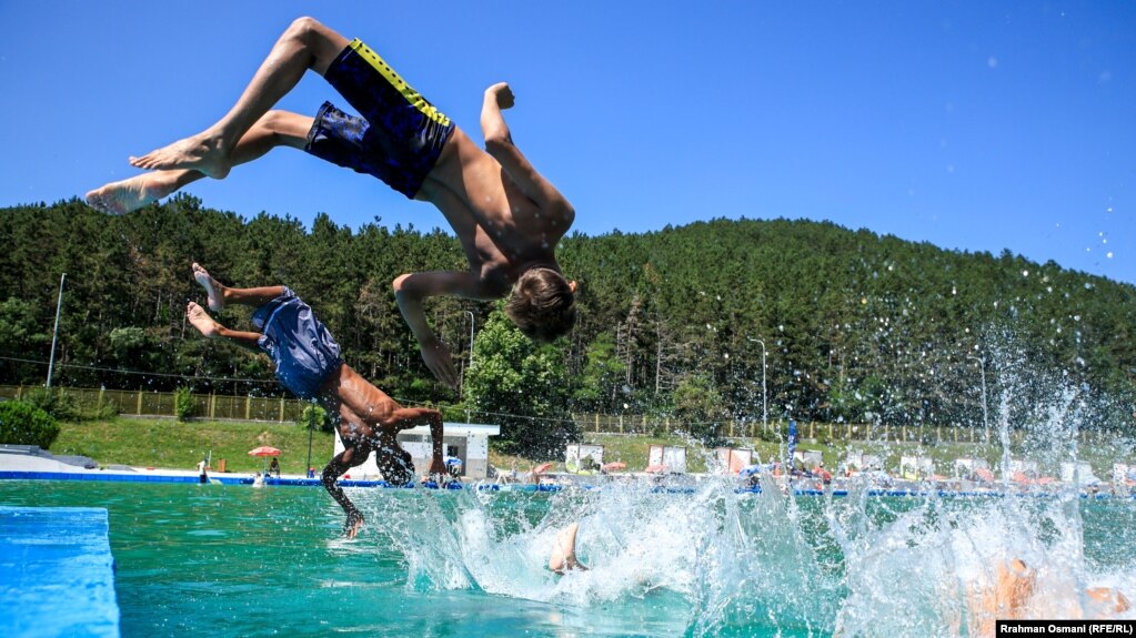 Dy fëmijë duke u zhytur në pishinë gjatë vapës së madhe në Prishtinë. 18 korrik 2023