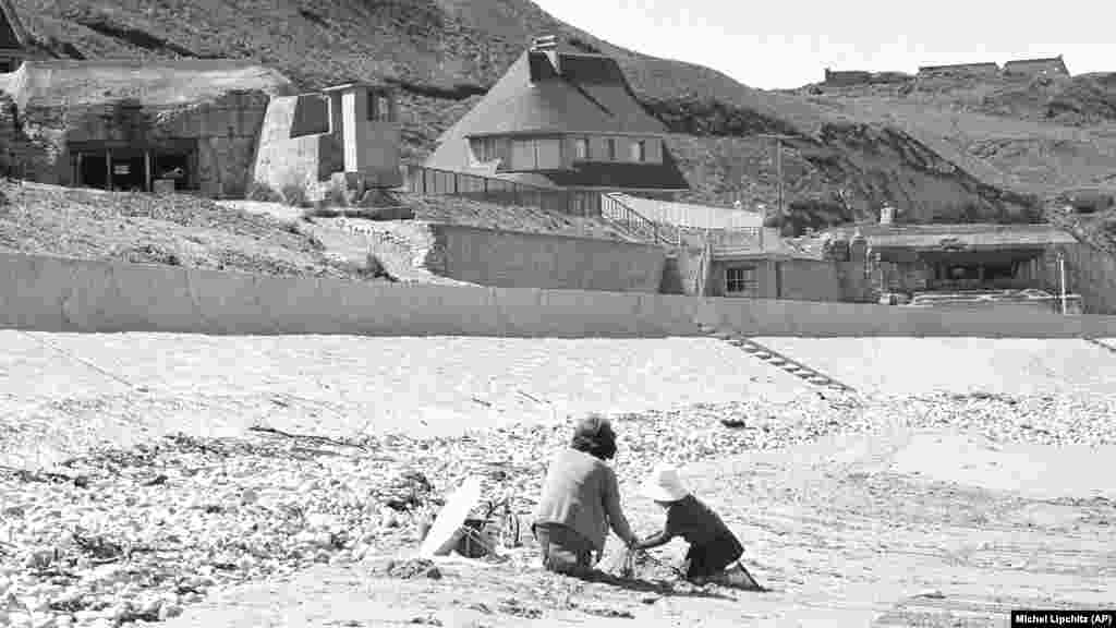 Francia gyerekek játszanak a vierville-sur-meri parton &ndash; amelyet Omaha Beach néven ismernek &ndash;, ahol még mindig állnak a német bunkerek 1964. június 6-án, húsz évvel a D-napi partraszállás után. Franciaország elnökeként eltöltött tizenegy éve alatt Charles de Gaulle nem vett részt a D-napi eseményeken.&nbsp;De Gaulle a világ vezetőit sem hívta meg a 25. évfordulóra 1969-ben