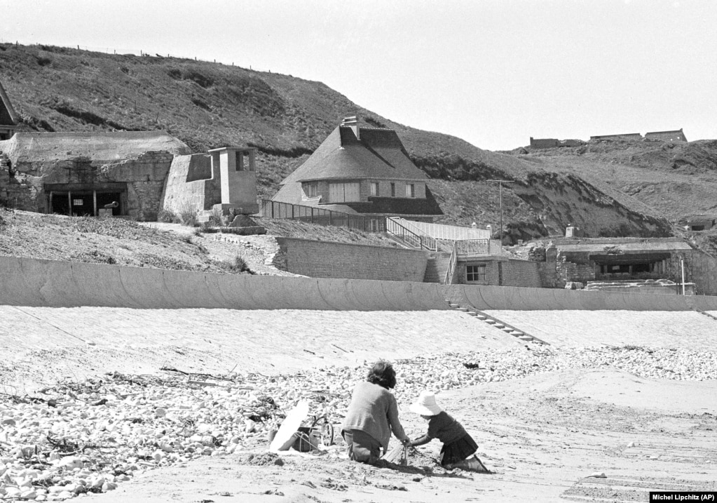 Fëmijët francezë duke luajtur në plazh në Vierville-sur-Mer - i njohur si Omaha Beach - ku bunkerët gjermanë qëndrojnë ende më 6 qershor 1964, 20 vjet pas Ditës D. Gjatë 11 vjetëve të tij si president i Francës, Charles de Gaulle refuzoi të merrte pjesë në ngjarjet e Ditës D. &ldquo;Ai refuzoi të përkujtonte 6 qershorin, duke pasur parasysh mënyrën se si ishte trajtuar kohën e zbarkimit të Ditës D. Ai nuk ishte përfshirë në diskutime apo në zbatimin e planit,&rdquo; thotë historiani Denis Peschanski. De Gaulle gjithashtu nuk i ftoi liderët botërorë në shënimin e 25-vjetorit më 1969.