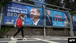 Një grua kalon pranë posterëve të presidentit aktual, Recep Tayyip Erdogan, dhe kundërkandidatit të tij, Kemal Kilicdaroglu. Sanliurfa, 28 prill 2023.