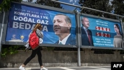 Женщина проходит мимо рекламных щитов с портретами кандидатов в президенты Турции Реджепа Тайипа Эрдогана (слева) и Кемаля Кылычдароглу. Шанлыурфа, Турция, 28 апреля 2023 года