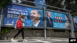 Женщина проходит мимо рекламных щитов с портретами кандидатов в президенты Турции Реджепа Тайипа Эрдогана (слева) и Кемаля Кылычдароглу. Шанлыурфа, Турция, 28 апреля 2023 года
