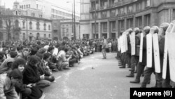 În Piața Romană din București, pe 22 decembrie, oamenii au îngenunchiat în fața militarilor trimiși să înăbușe revoluția. În aceeași zi, Ceaușescu fugea, iar gen. Victor Atanasie Stănculescu cere trupelor să intre în cazărmi. S-a murit în continuare.