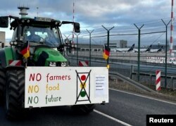 Трактор протестующих фермеров у летного поля международного аэропорта во Франкфурте-на-Майне (Германия)