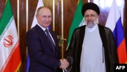 Ebrahim Raiszi iráni elnök (jobbra) üdvözli Vlagyimir Putyin orosz elnököt Teheránban 2022. július 19-én