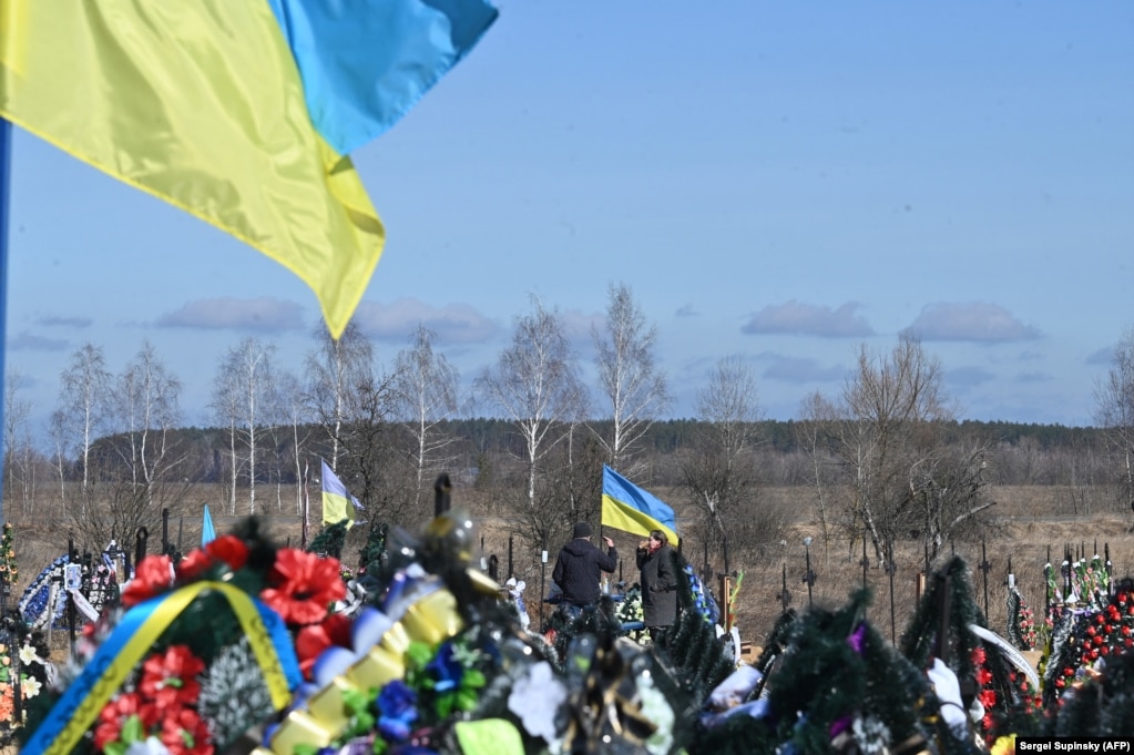 Familjarët pinë në kujtim të ushtarëve të rënë në Borodianka, afër Kievit, në mars 2023.