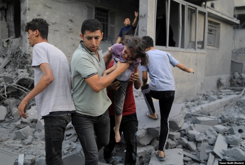 Disa djem duke mbajtur një vajzë palestineze të plagosur, e cila u shpëtua nga rrënojat e një shtëpie pasi ajo u godit nga sulmet izraelite, në Khan Younis, më 14 tetor 2023