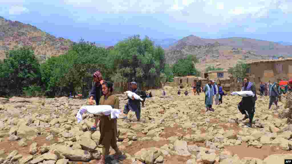 People carry the bodies of children who died in flash floods in Afghanistan&#39;s central Maidan Wardak Province on July 23. Over the past three days, seasonal rains caused flooding that killed at least 31 people and left dozens missing.